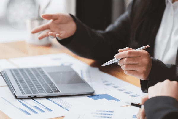 Tax attorney for IRS debt relief consulting with client over financial documents and laptop in professional office setting