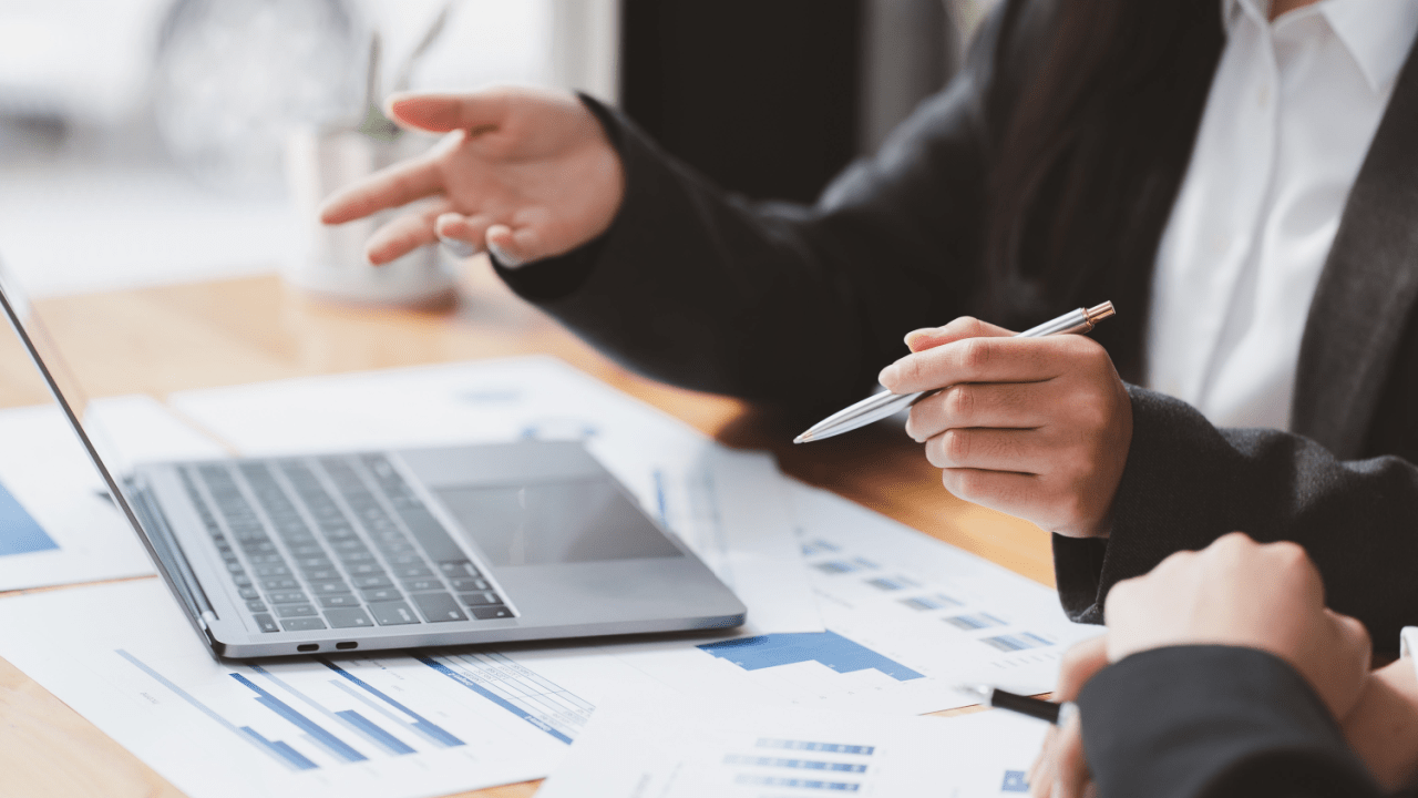 Tax attorney for IRS debt relief consulting with client over financial documents and laptop in professional office setting