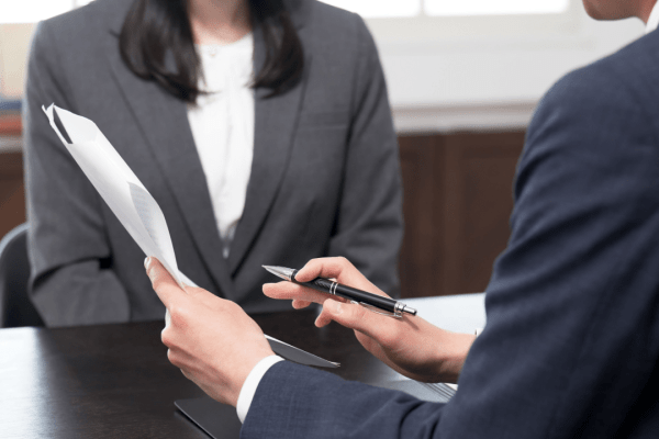 Tax attorney consulting with client about IRS debt relief strategies during professional meeting with legal documents and note-taking