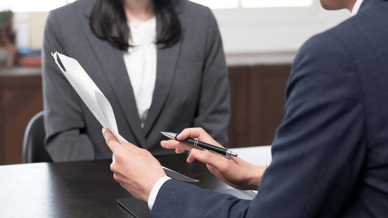 Tax attorney consulting with client about IRS debt relief strategies during professional meeting with legal documents and note-taking