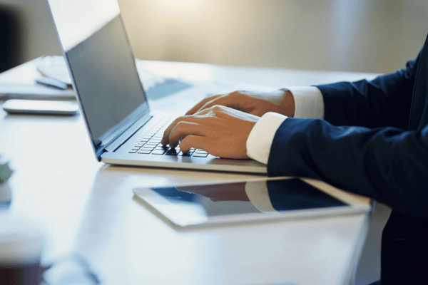 Professional tax lawyer working on laptop explaining tax lawyer fees and costs to clients in modern office setting