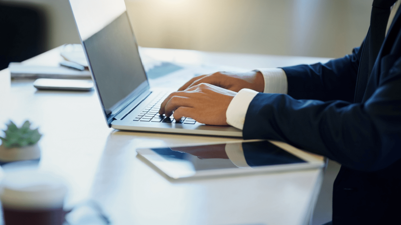 Professional tax lawyer working on laptop explaining tax lawyer fees and costs to clients in modern office setting