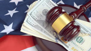Wooden gavel and US dollar bills on American flag representing factors that affect tax attorney fees