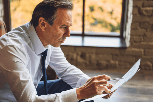 Businessman reviewing documents wondering can I settle my IRS tax debt with professional tax attorney help