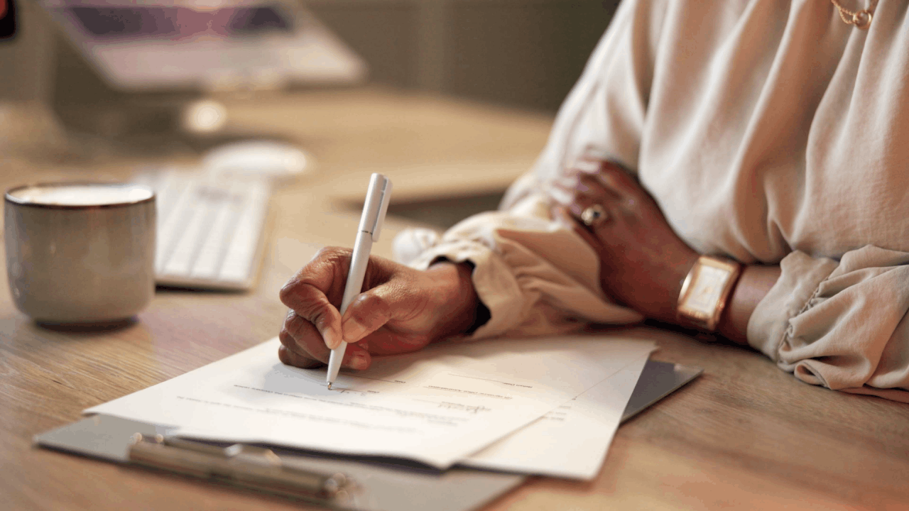 Woman reviewing financial documents and taking notes about does settling with the IRS hurt your credit while sitting at desk with coffee