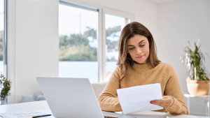 Woman reviewing tax documents to learn how to qualify for the IRS Fresh Start Program at home office desk