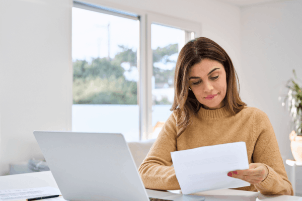 Woman reviewing tax documents to learn how to qualify for the IRS Fresh Start Program at home office desk