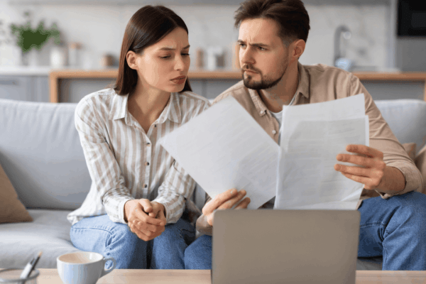 Worried couple reviewing tax documents to determine what debts qualify for the fresh start program
