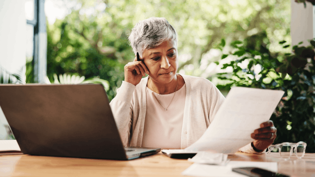Woman on phone reviewing tax documents wondering what happens if you owe the IRS more than $25,000