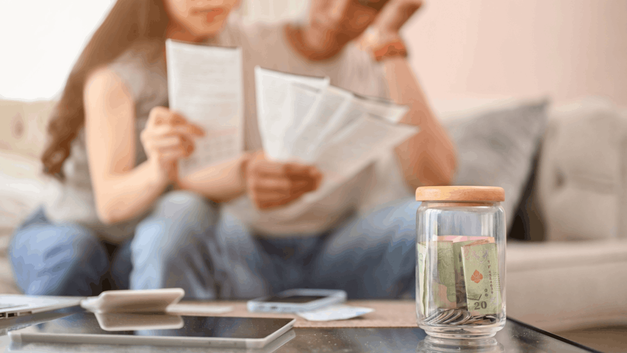 Worried couple reviewing IRS notices wondering can the IRS take my wages for my spouse's debt while looking at savings jar