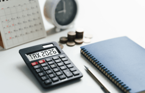 Am I in trouble if I get audited — calculator displaying TAX 2026 with coins, clock, and notebook representing IRS audit preparation