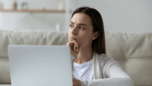 Concerned woman sitting with laptop wondering how likely are my taxes to be audited while reviewing financial documents