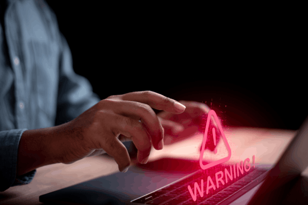 A person typing on a laptop with a glowing red warning symbol — representing what income level triggers an audit and the urgency of IRS audit risk