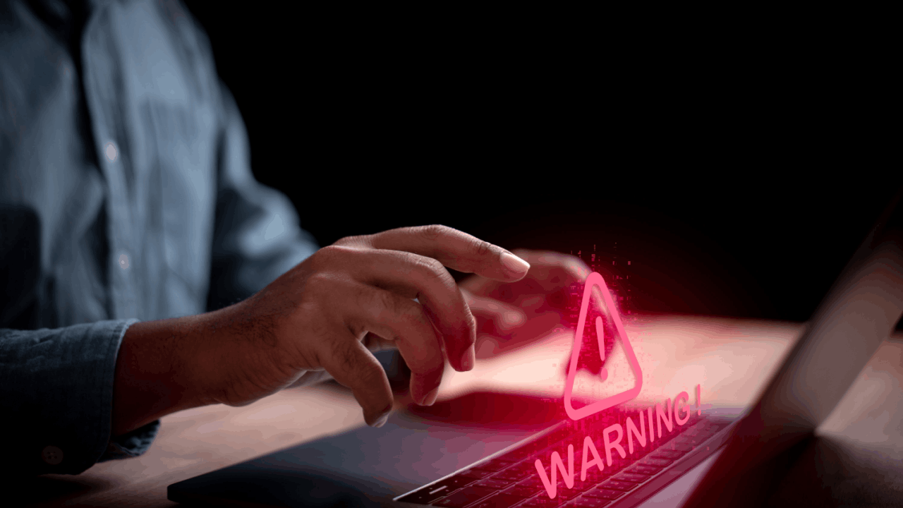 A person typing on a laptop with a glowing red warning symbol — representing what income level triggers an audit and the urgency of IRS audit risk