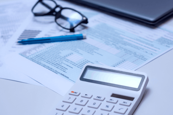What is the fine if you get audited — calculator, tax documents, glasses, and pen on a desk representing IRS audit penalty review
