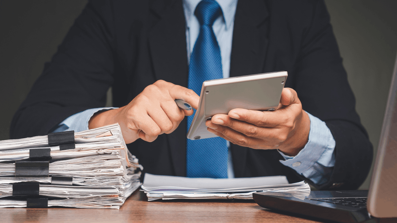Tax professional reviewing financial documents and using a calculator to assess IRS audit risk for who gets audited the most by the IRS