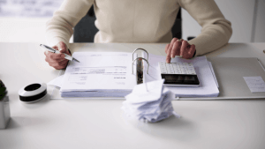 A person reviewing tax invoices and using a calculator — illustrating who is most likely to get audited by the IRS