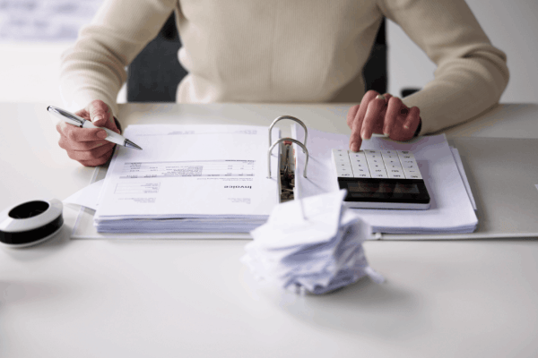 A person reviewing tax invoices and using a calculator — illustrating who is most likely to get audited by the IRS