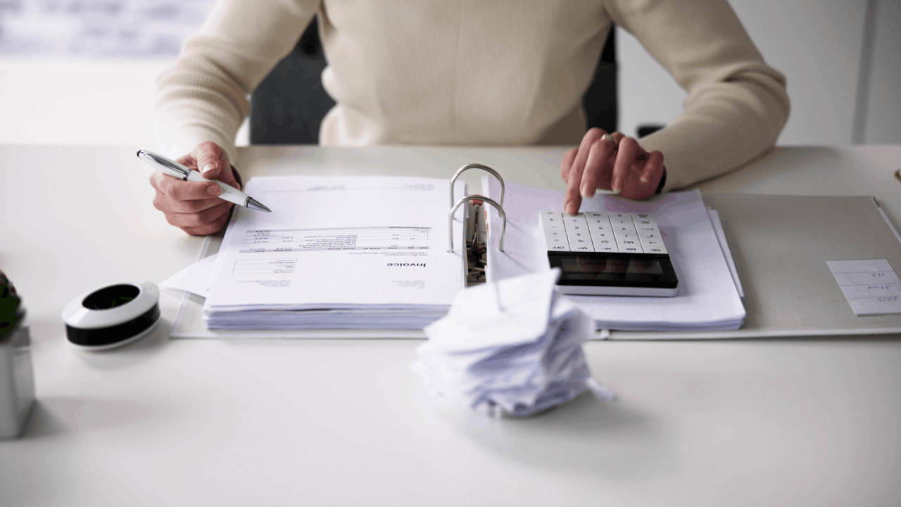 A person reviewing tax invoices and using a calculator — illustrating who is most likely to get audited by the IRS