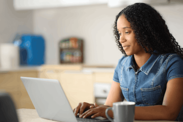 Bonus depreciation – woman smiling while researching business tax deductions on a laptop at home