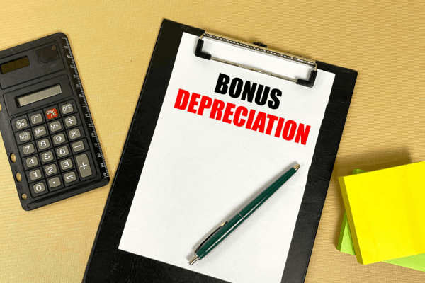 Bonus depreciation explained on clipboard with calculator and notepad