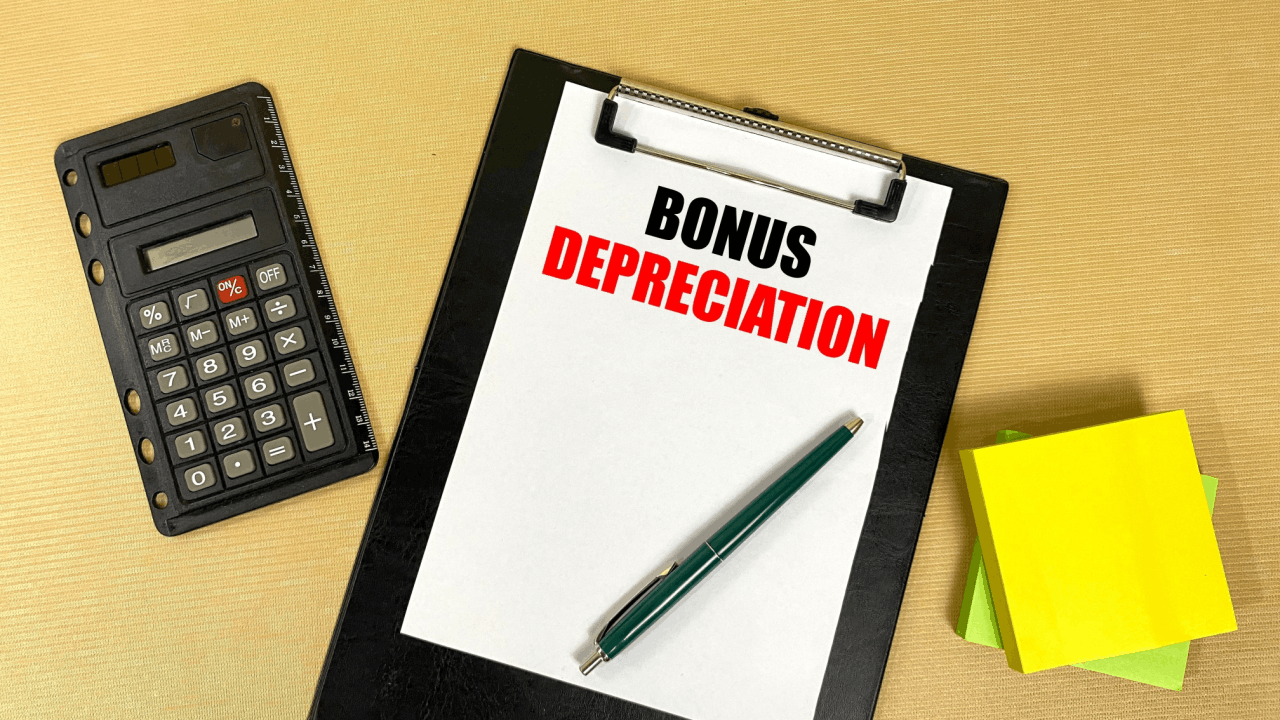 Bonus depreciation explained on clipboard with calculator and notepad