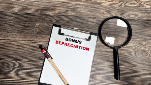 What qualifies for bonus depreciation – clipboard with bold text on wooden desk with magnifying glass and pen