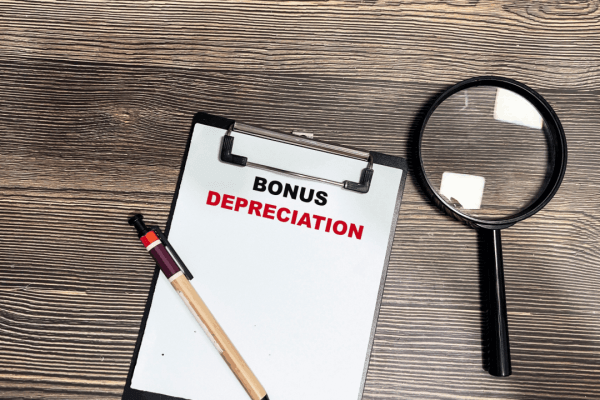 What qualifies for bonus depreciation – clipboard with bold text on wooden desk with magnifying glass and pen