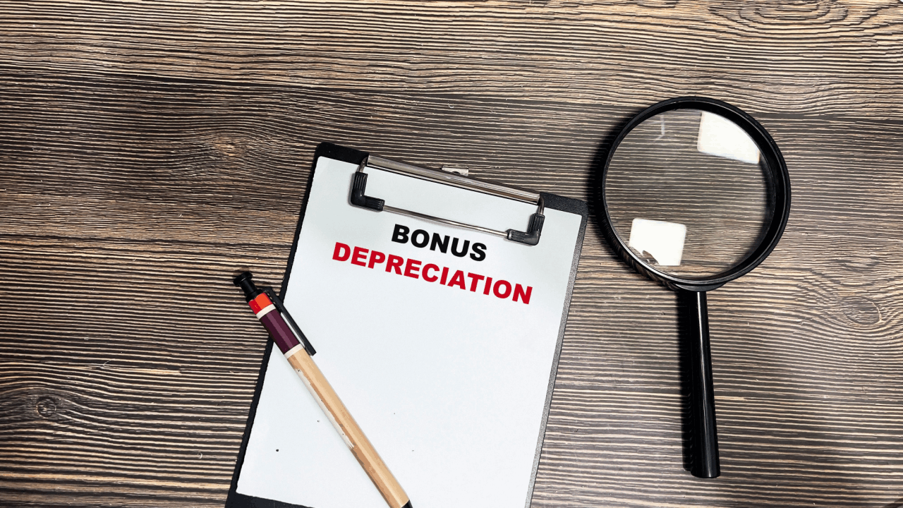 What qualifies for bonus depreciation – clipboard with bold text on wooden desk with magnifying glass and pen