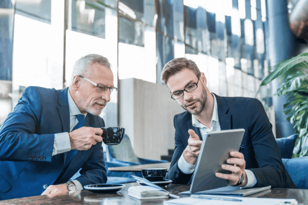 Two businessmen reviewing IRS wage garnishment information on a tablet during a professional consultation