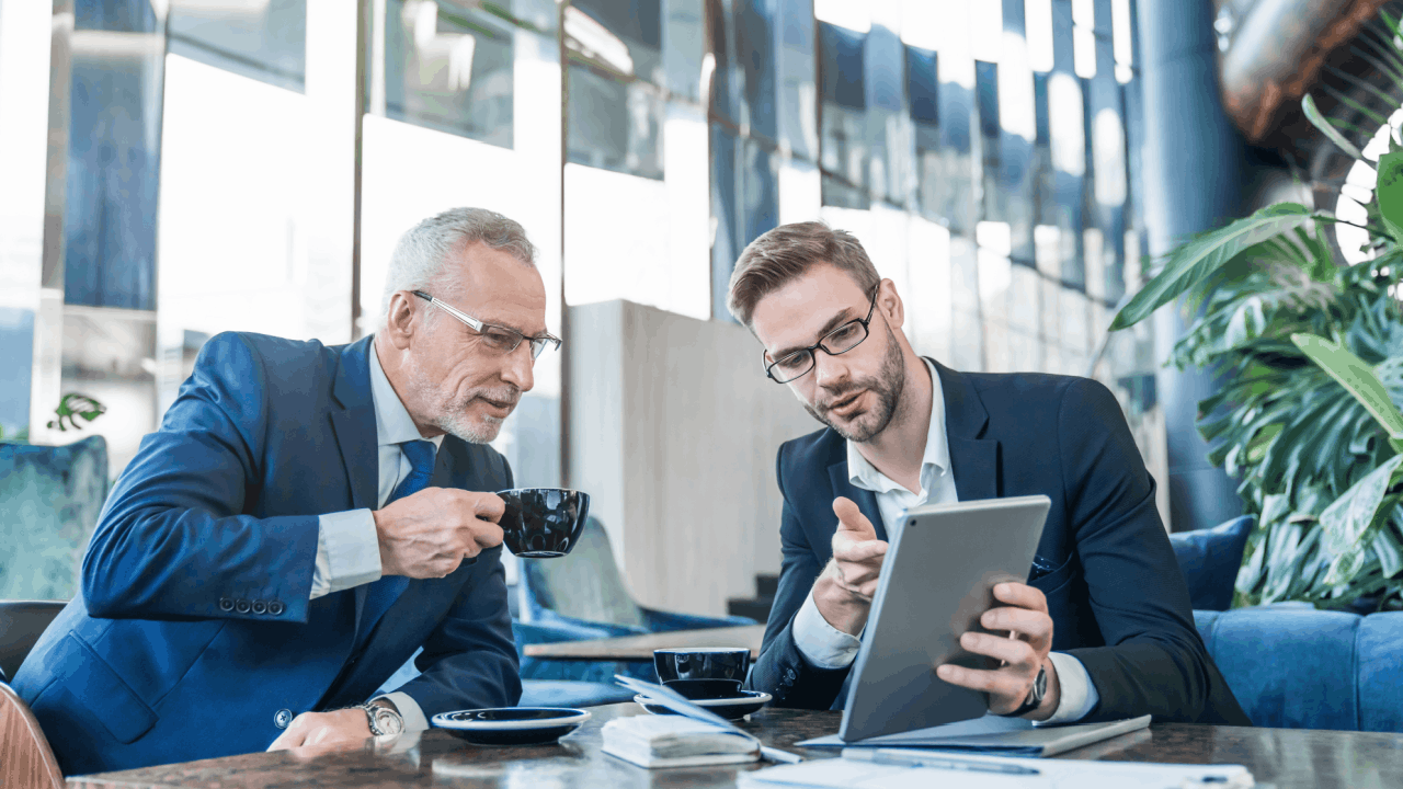 Two businessmen reviewing IRS wage garnishment information on a tablet during a professional consultation