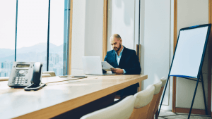 Section 179 vs bonus depreciation – businessman reviewing tax documents at a conference table with a laptop in a high-rise office