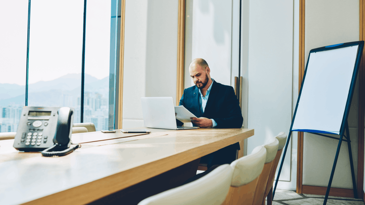 Section 179 vs bonus depreciation – businessman reviewing tax documents at a conference table with a laptop in a high-rise office