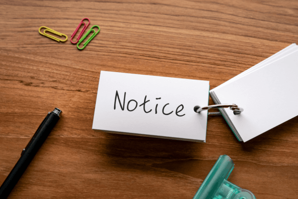 Notice card on ring binder with pen and colorful paper clips on wooden desk