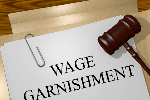 Wage garnishment legal document with gavel and paper clip on wooden surface